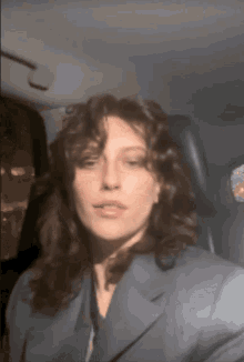 a woman with curly hair is sitting in a car and looking at the camera