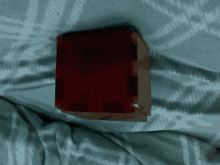 a red cube is laying on a bed