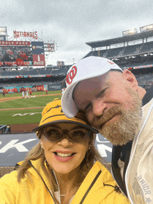 a man and a woman pose for a picture in front of a nationals park sign