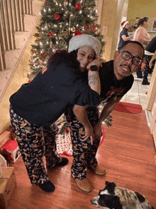 a man and a woman standing in front of a christmas tree