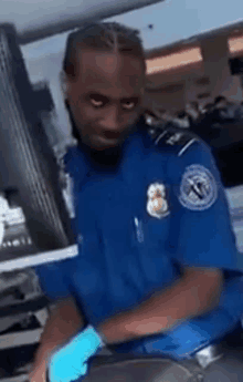 a man in a blue uniform and blue gloves is standing in front of a monitor .