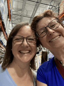 two women wearing glasses are posing for a picture in a store