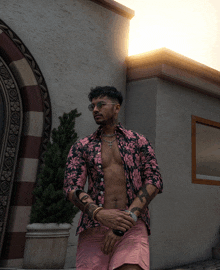 a shirtless man wearing a floral shirt and pink shorts