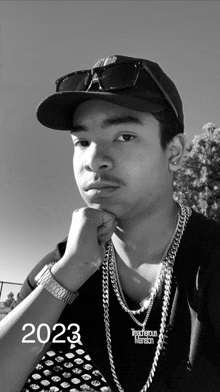 a black and white photo of a man wearing a hat and a necklace with the year 2023 on it