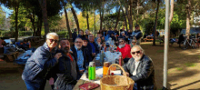 a group of people are posing for a picture while sitting at a picnic table