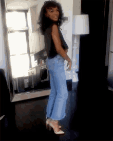 a woman in jeans and heels is standing in a room