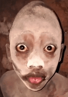 a child with white paint on his face is making a funny face .