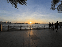 a sunset over a body of water with a city skyline in the distance