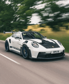 a white porsche gt3 is driving down a road