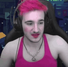 a man with pink hair and a necklace is wearing headphones and lipstick .