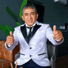 a man in a tuxedo and tie gives a thumbs up