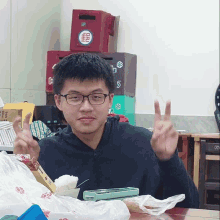 a man giving a peace sign in front of a stack of boxes that say ' s ' on them