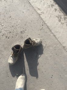 a pair of shoes laying on the ground next to a person 's foot