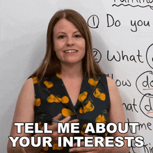 a woman stands in front of a white board with the words tell me about your interests written on it