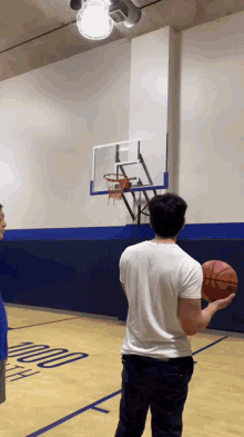 a man in a white shirt is holding a basketball in front of a basketball hoop that has the number 200 on it