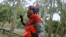 a man wearing a red jacket and a blue and red hat with the word eagles on it is running through the woods