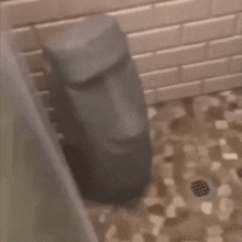 a statue of a face is sitting on a tiled floor in a bathroom