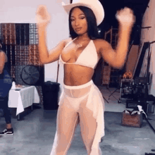 a woman in a bikini and a cowboy hat is dancing .