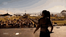 a woman stands on a stage in front of a crowd at a music festival with a caption that says gascolla