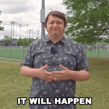 a man in a blue shirt stands in front of a field with the words " it will happen " above him