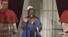 a woman in a blue dress is clapping in front of a group of cardinals