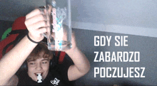 a man holds up a glass with the words " gdy sie zabardzo poczujesz " written on the bottom