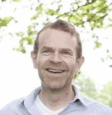 a man with a beard and a blue shirt is smiling