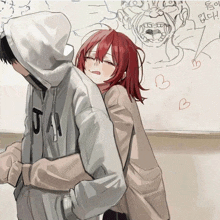 a girl with red hair is hugging a boy wearing a hoodie that says j.a.