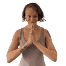 a woman with a tattoo on her arm holds her hands together and smiles