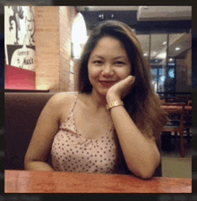 a woman sitting at a table with her hand on her chin in front of a sign that says max