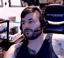 a man with a beard wearing headphones and a gtracing gaming chair