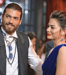 a man with a beard and a woman in a blue dress are standing next to each other