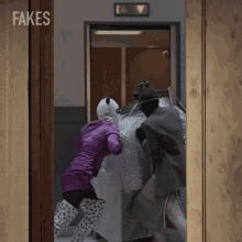 a woman in a panda mask pushes a man in a bubble wrap suit through an elevator with fakes written on the door