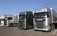 three scania trucks are parked next to each other in a parking lot