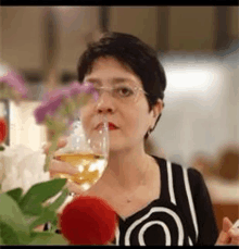 a woman is drinking a glass of wine at a table .