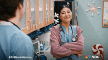 a woman with a stethoscope around her neck stands in a kitchen with a nbc logo on the bottom right