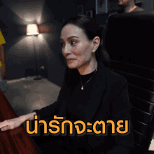 a woman sits at a desk with the words " น่า รัก จะ ตาย " written on the bottom