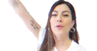 a woman with a tattoo on her arm is smiling and holding up her arm .