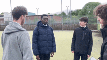 a group of young men are standing in a circle and one of them is wearing a jacket with the letter a on it