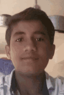 a young boy is taking a selfie with a ceiling fan behind him .