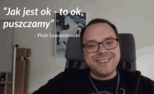 a man wearing glasses is smiling in front of a quote by piotr lewandowski