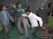 a group of men are dancing together in a room on make a gif .