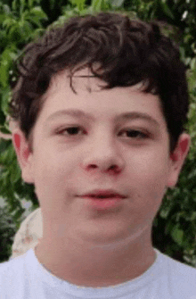 a close up of a young boy 's face with a white shirt on .