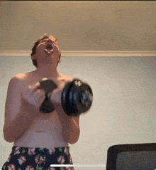 a shirtless man is lifting a dumbbell with his tongue hanging out