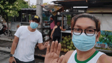 a man and a woman wearing face masks are standing in front of a sign that says ' fresh '