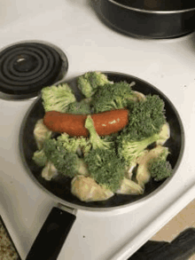 a pan filled with broccoli , dumplings and a sausage on a stove top .