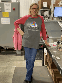 a woman wearing a roosters shirt stands in front of a machine