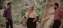 two men and a woman are standing next to each other in the jungle