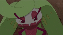 a close up of a cartoon character with green wings and a red face .