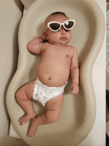 a baby wearing sunglasses is laying on a changing mat